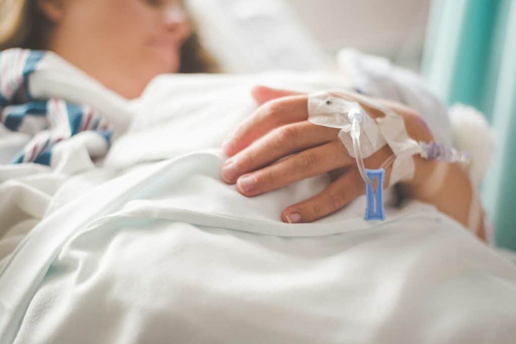 Woman laying in a hospital bed with an IV in her hand, representing the importance of medical power of attorney in healthcare decisions.